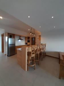 a kitchen with a bar with chairs and a refrigerator at Paille en Queue apartment in Grand Baie