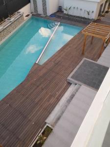 a swimming pool with a wooden deck and a bench at Paille en Queue apartment in Grand Baie