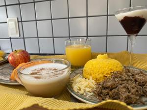 una mesa con un plato de comida y dos vasos de zumo de naranja en Casa de Odoya, en Caucaia