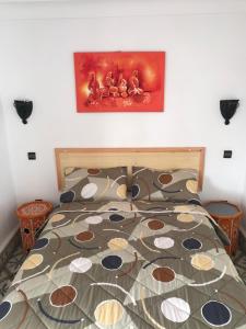 een slaapkamer met een bed met een schilderij aan de muur bij Riad chez brahim in Essaouira