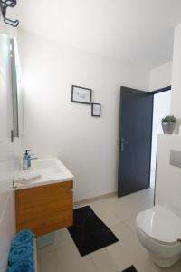 a bathroom with a white toilet and a sink at Appart' Bleu Soleil in Filaos