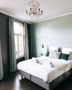 a bedroom with a large white bed with a chandelier at Domus Portus in Dendermonde