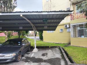a car parked under a cover in a parking lot at Eden 8pax 3Rooms apartment near Kuching Airport in Kuching