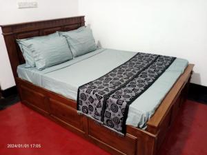 ein Bett in einem Schlafzimmer mit einem Bettrahmen aus Holz in der Unterkunft Gunam Residence in Kattankudi