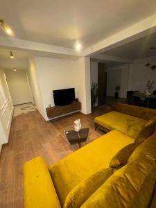 a living room with two yellow couches and a television at Vodno Apartment Skopje in Skopje