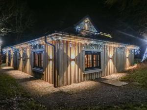 een houten huis met 's nachts verlichting bij Spacious holiday home in the woods in Bastenaken