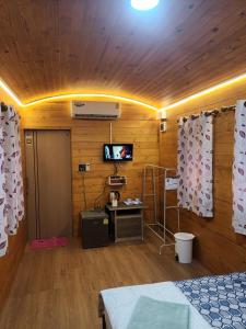Habitación con cama y TV en una pared de madera. en ชายเขาโฮมสเตย์ en Kanchanaburi