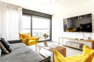 a living room with yellow chairs and a tv at Sea of Galilee Panorama Apartment by Sea N' Rent in Tiberias