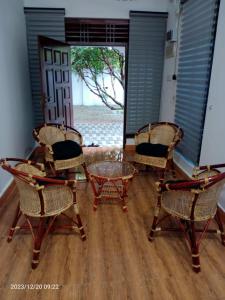 une chambre avec trois chaises et une table en verre dans l'établissement Gunam Residence, à Kattankudi