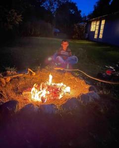 Una persona seduta intorno al fuoco in un cortile di Hyggeligt idyllisk hus a Rønde