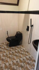 a bathroom with a black toilet and a sink at Kaliningrad Cottage in Sidomukti