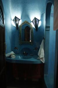 Baño azul con lavabo y espejo en Riad Azenzer en Marrakech