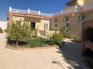 ein großes Backsteingebäude mit Bäumen davor in der Unterkunft Beautiful private villa Magawhish in Hurghada