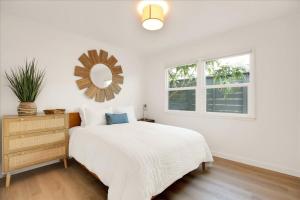 a white bedroom with a bed and a mirror at Shoreline Cottage in Santa Barbara