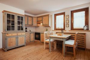 uma cozinha com armários de madeira e uma mesa e cadeiras em Hotel Alpenrose em Arabba