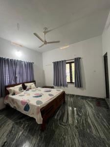 1 dormitorio con 1 cama y ventilador de techo en Mount River Homestay, en Palakkad