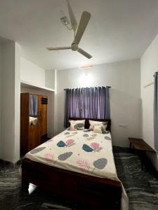 1 dormitorio con 1 cama grande y ventilador de techo en Mount River Homestay, en Palakkad