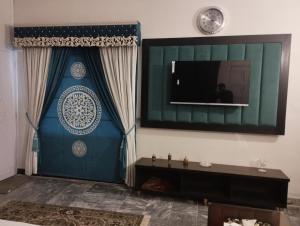 a living room with a television on a wall at Shelton House in Karachi