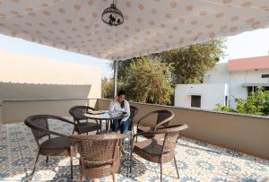 eine Person, die an einem Tisch auf einer Terrasse sitzt in der Unterkunft The Deck in Jaipur
