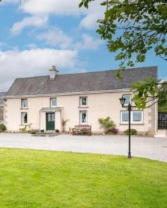 a large white house with a bench in the grass at Sweet Lamb Farmhouse in New Ross