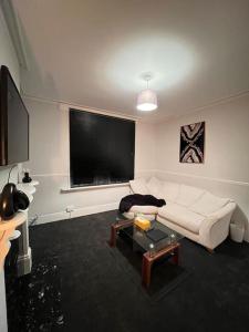 a living room with a white couch and a flat screen tv at Home in Sheffield City Centre in Heeley