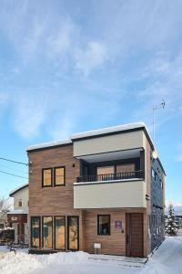 - un bâtiment en aominium avec une façade en bois dans la neige dans l'établissement KOYO・YUKI, à Furano