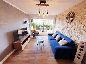 sala de estar con sofá azul y TV en Le Combo Parfait entre Mer et Nature, en Villers-sur-Mer