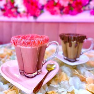 duas chávenas de bebidas cor-de-rosa em pratos com uma colher em Casa da Marlene em Guaramiranga