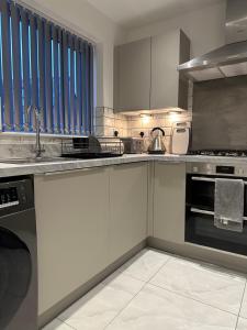 a kitchen with white cabinets and a sink at Lush Place in Manchester