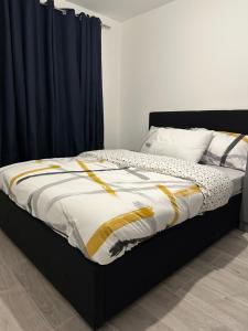 a bed with a black frame and yellow and white comforter at Lush Place in Manchester