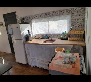 uma cozinha com um frigorífico branco e uma mesa em Cabaña Balneario buenos aires em Balneario Buenos Aires