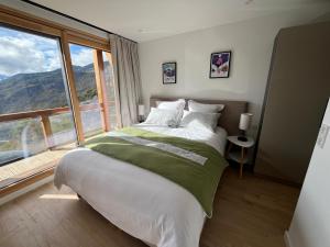 a bedroom with a large bed and a large window at Chalet La Tarine 