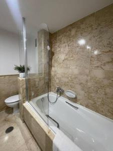 a bathroom with a bath tub and a toilet at Apartamento Verde en Sotogrande in Sotogrande