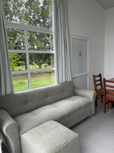 a living room with a couch and a large window at Complejo Las Palmeras in Colonia del Sacramento