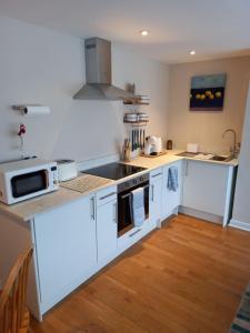 a kitchen with white cabinets and a stove top oven at Laurel Apartment in Bourton on the Water