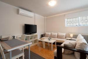 een woonkamer met een bank en een tv bij Bright, Cosy Studio close to Glyfada Beach & Center in Athene
