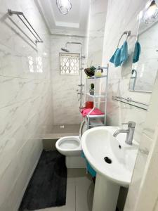 a white bathroom with a sink and a toilet at Precious Palace in Accra