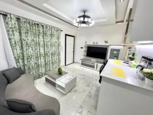 ein weißes Wohnzimmer mit einem TV und einem Sofa in der Unterkunft Precious Palace in Accra