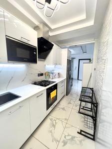 uma cozinha com armários brancos e um forno com placa de fogão em Precious Palace em Acra