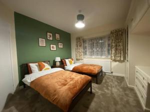 a bedroom with two beds and a green wall at Oadby Town Mid-Century Bungalow in Oadby