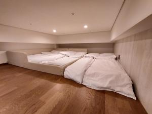 Cama blanca grande en habitación con suelo de madera en Coex Stay en Seúl