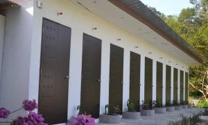 a row of doors on the side of a building with flowers at Sailor's Rest in Kampung Janda Baik