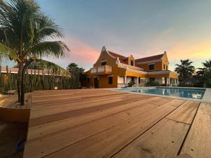 克拉倫代克的住宿－Landhuis Belnem Bonaire，一座房子,设有木甲板,毗邻一个游泳池