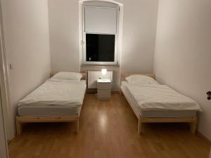two beds in a small room with a window at Komfortable Wohnung in Magdeburg