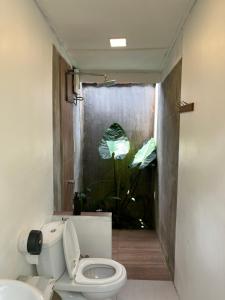 a bathroom with a toilet and a window with a plant at Sailor's Rest in Kampung Janda Baik