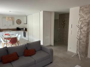 ein Wohnzimmer mit einem grauen Sofa und einer Küche in der Unterkunft vacances en Ardéche "maison Chauvet" in Vallon-Pont-dʼArc