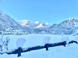 a fence covered in snow with mountains in the background at Apartment WEITBLICK in Wald im Pinzgau