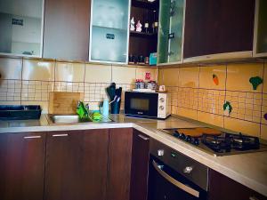 cocina con armarios de madera, microondas y fregadero en Apartman “Zara” en Zagreb