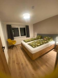 een slaapkamer met een groot bed en een gele stoel bij Appartement Tannenhof I in Ramsau am Dachstein