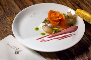 a white plate with food on a wooden table at Hôtel Les Servages d'Armelle in Les Carroz d'Araches